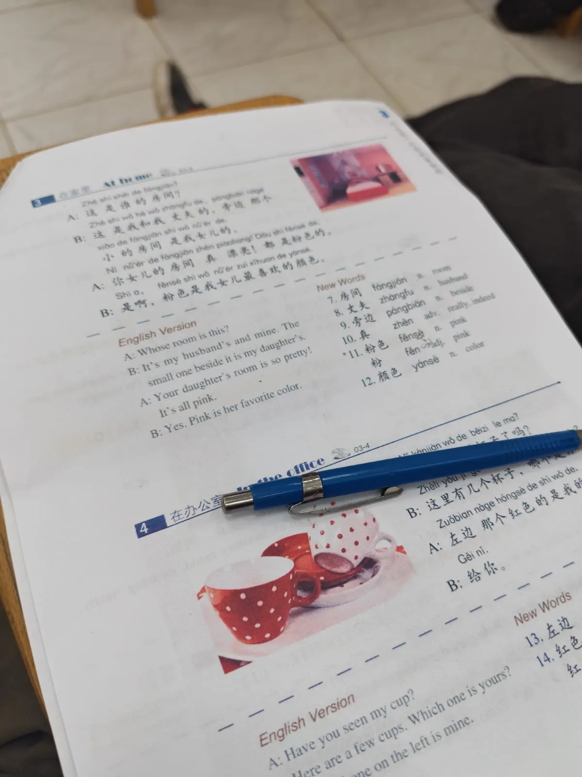 An open Chinese language workbook with a blue pen resting across the page